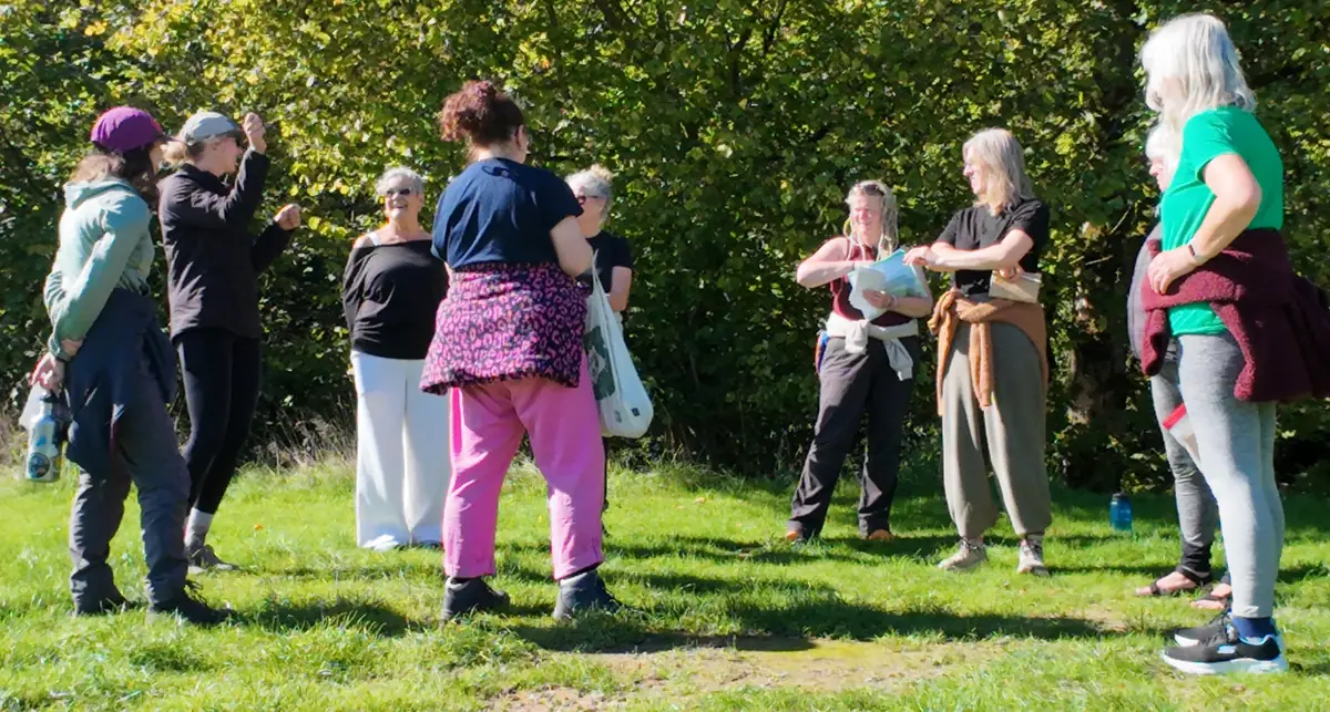 A circle of women chatting and laughing together on a sunny meadow